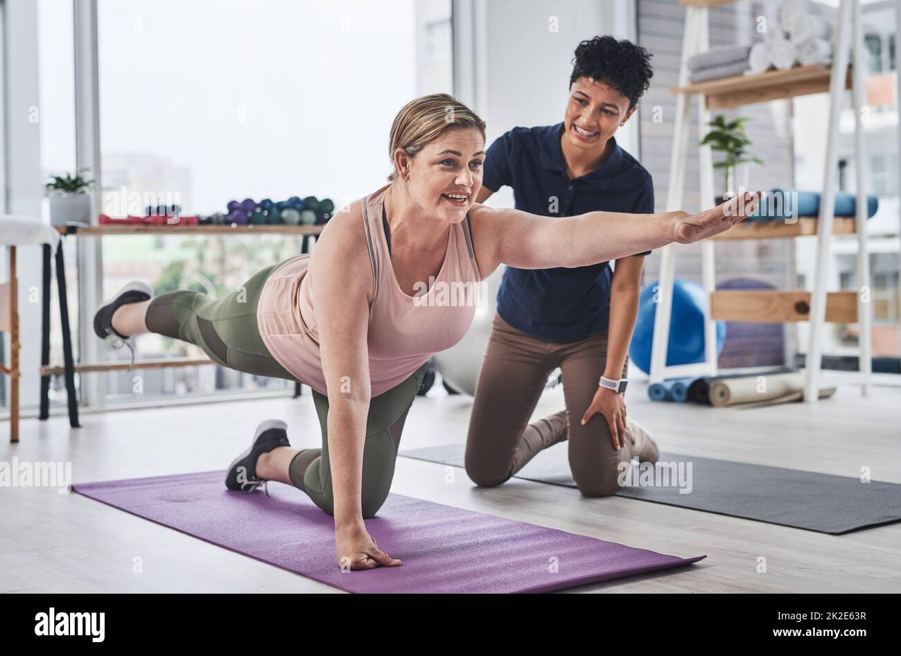 Le yoga fait tant de points positifs pour votre corps. Prise de vue en longueur d'une femme mature faisant des exercices d'équilibre et de mouvement avec son physiothérapeute dans un centre de réadaptation. Banque D'Images