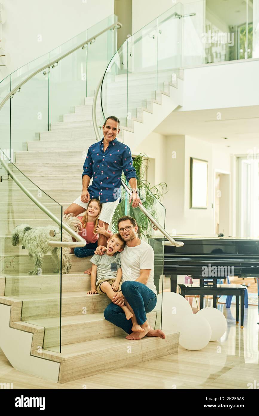 Deux dads sont mieux qu'un. Portrait en longueur d'une famille affectueuse de quatre personnes dans les escaliers à la maison. Banque D'Images