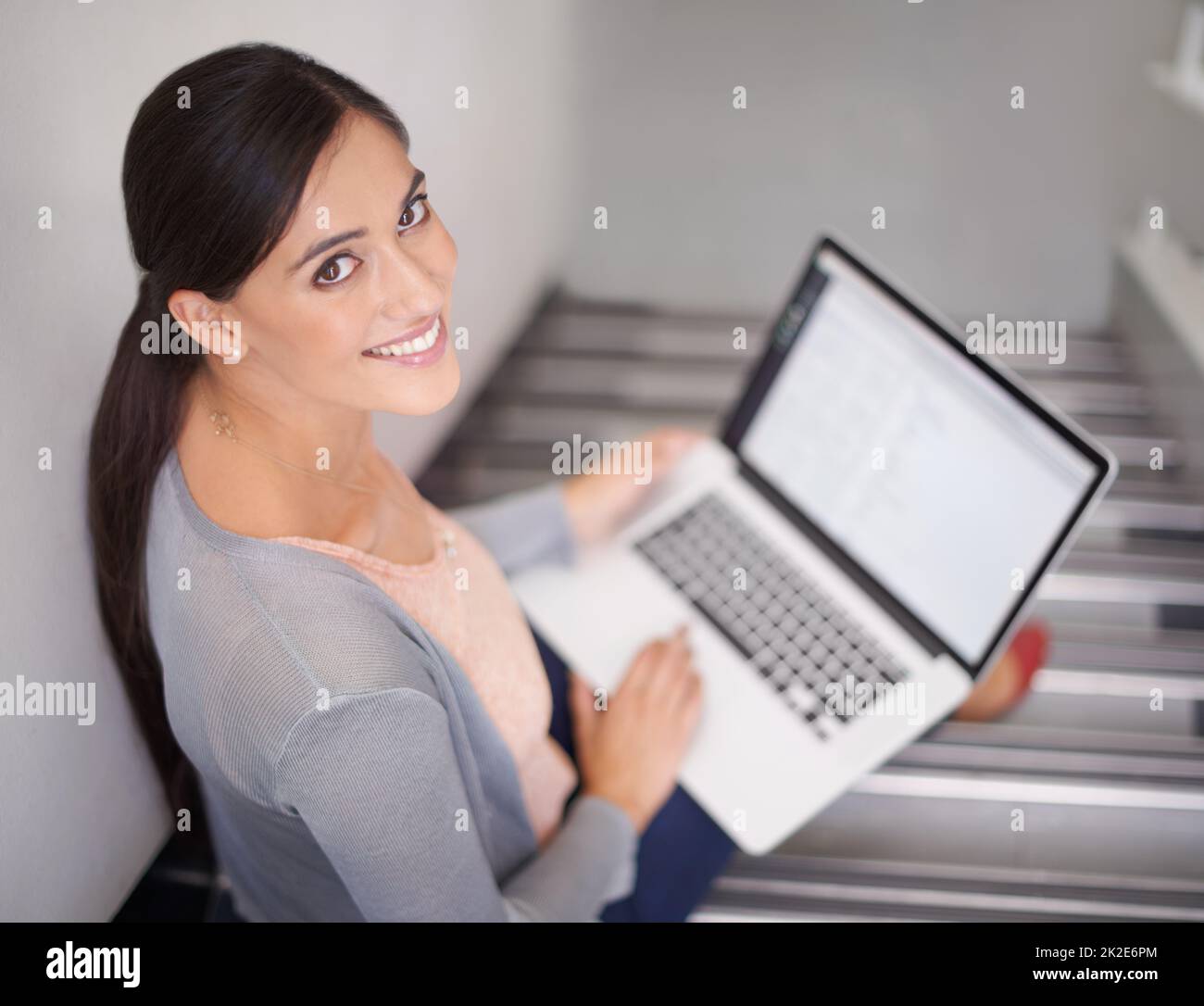 Obtenir un peu de travail avant la classe. Portrait d'une jeune femme assise dans un escalier à l'aide d'un ordinateur portable. Banque D'Images