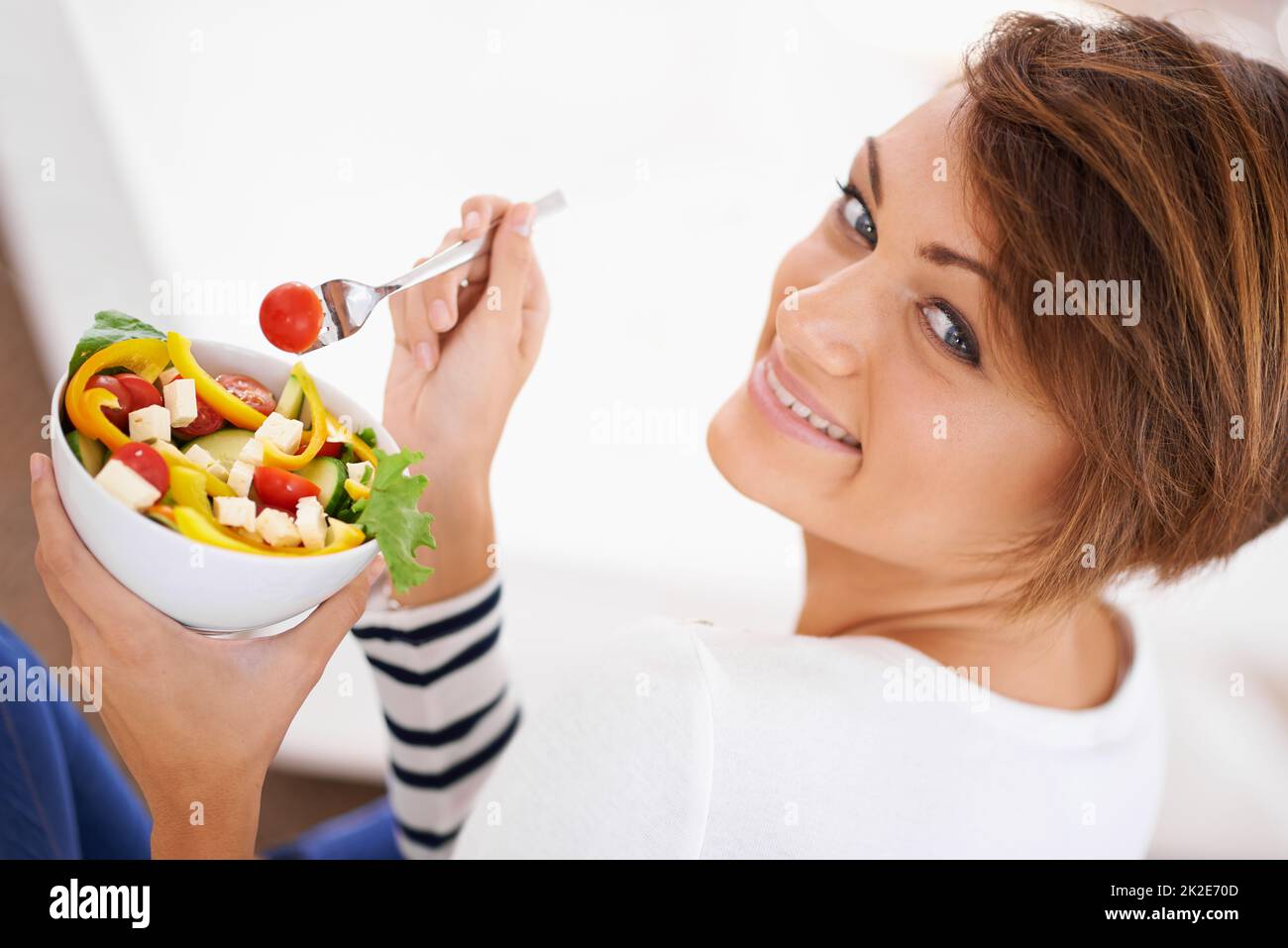 Manger de la salade avec un raboueur. Prise de vue d'une jeune femme gaie en train de manger une salade. Banque D'Images