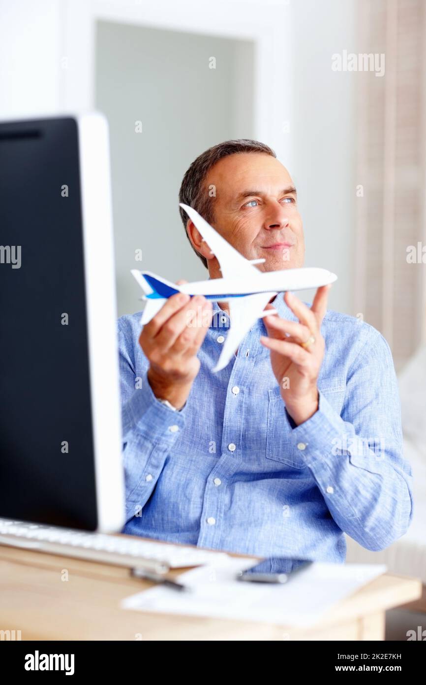 Planification du voyage - heureux homme mature tenant l'avion jouet à la maison. Voyage de planification - Portrait d'un homme heureux et mature avec un avion jouet à la maison. Banque D'Images