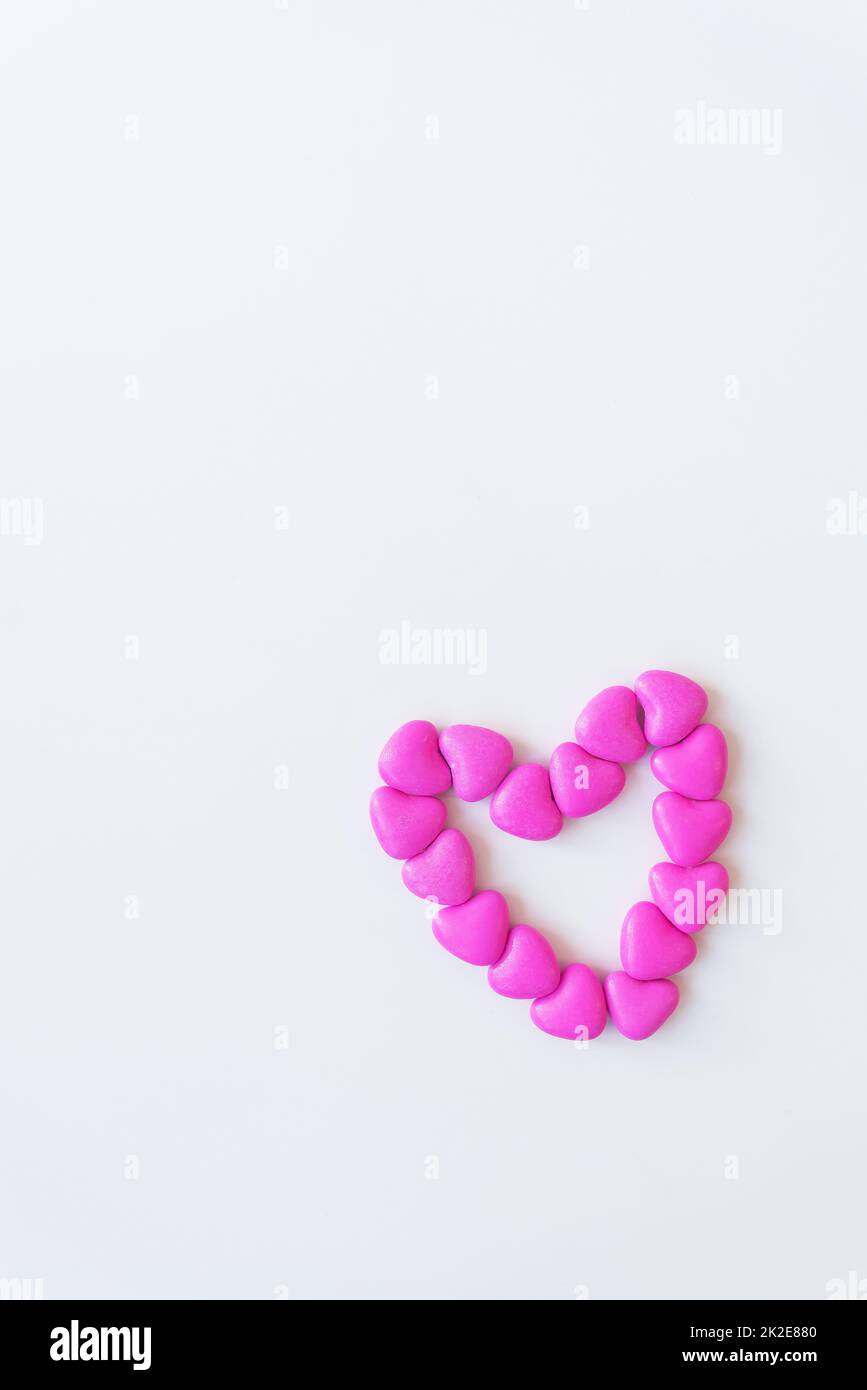 Saint-Valentin motif de jour fond plat couché dessus vue de coeur en forme de bonbons roses éparpillés sur fond blanc. Banque D'Images