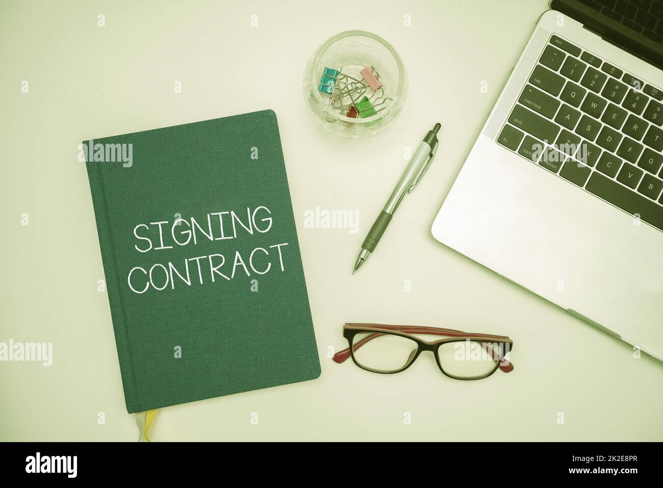 Légende de texte présentant le contrat de signature. Idée d'affaires les parties signataires du document acceptent les termes fournitures de bureau sur le bureau avec clavier et lunettes et tasse à café pour le travail Banque D'Images