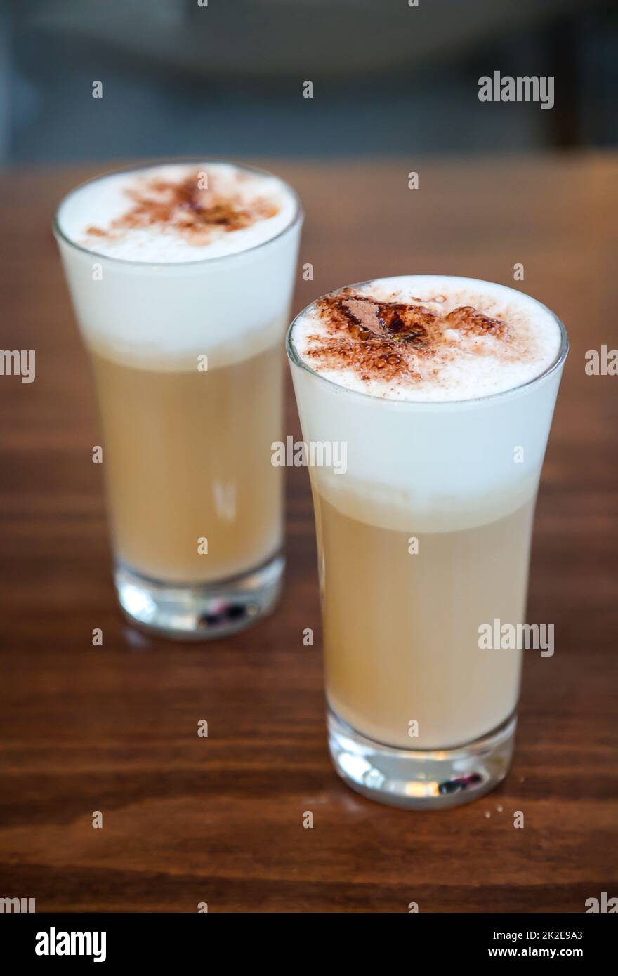 Deux verres de café latte arrosé de poudre de cacao. Banque D'Images