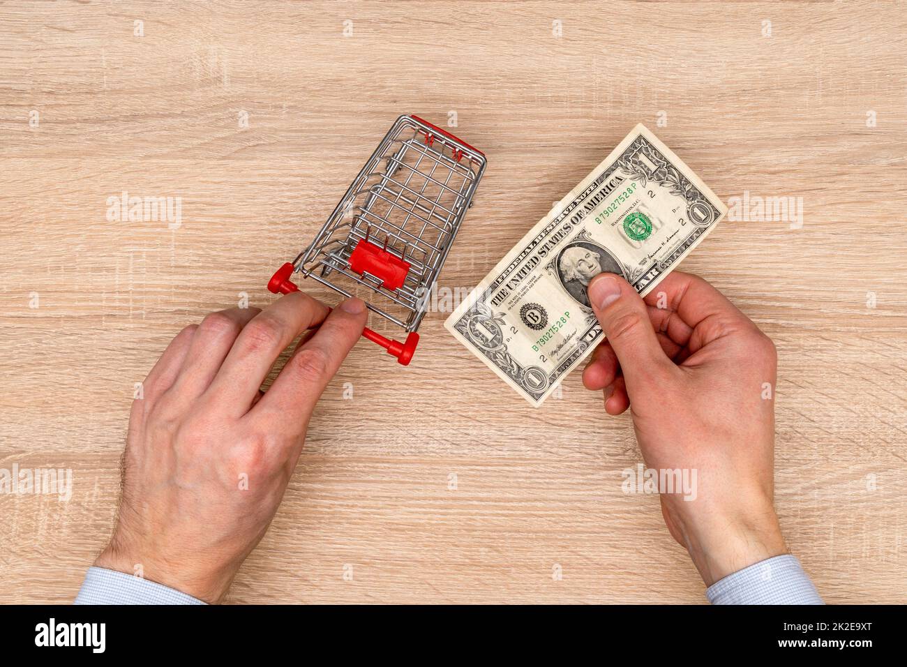 L'homme d'affaires pousse le chariot à jouets et tient une facture d'un dollar dans la main Banque D'Images