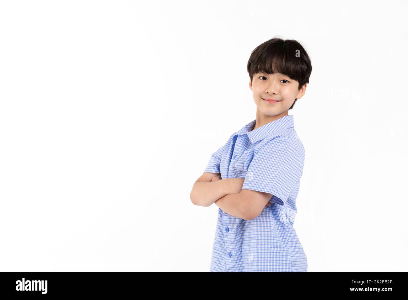 Jeune garçon coréen portant une chemise à demi-manche bleu d'été sur fond blanc studio croisant les bras souriant Banque D'Images