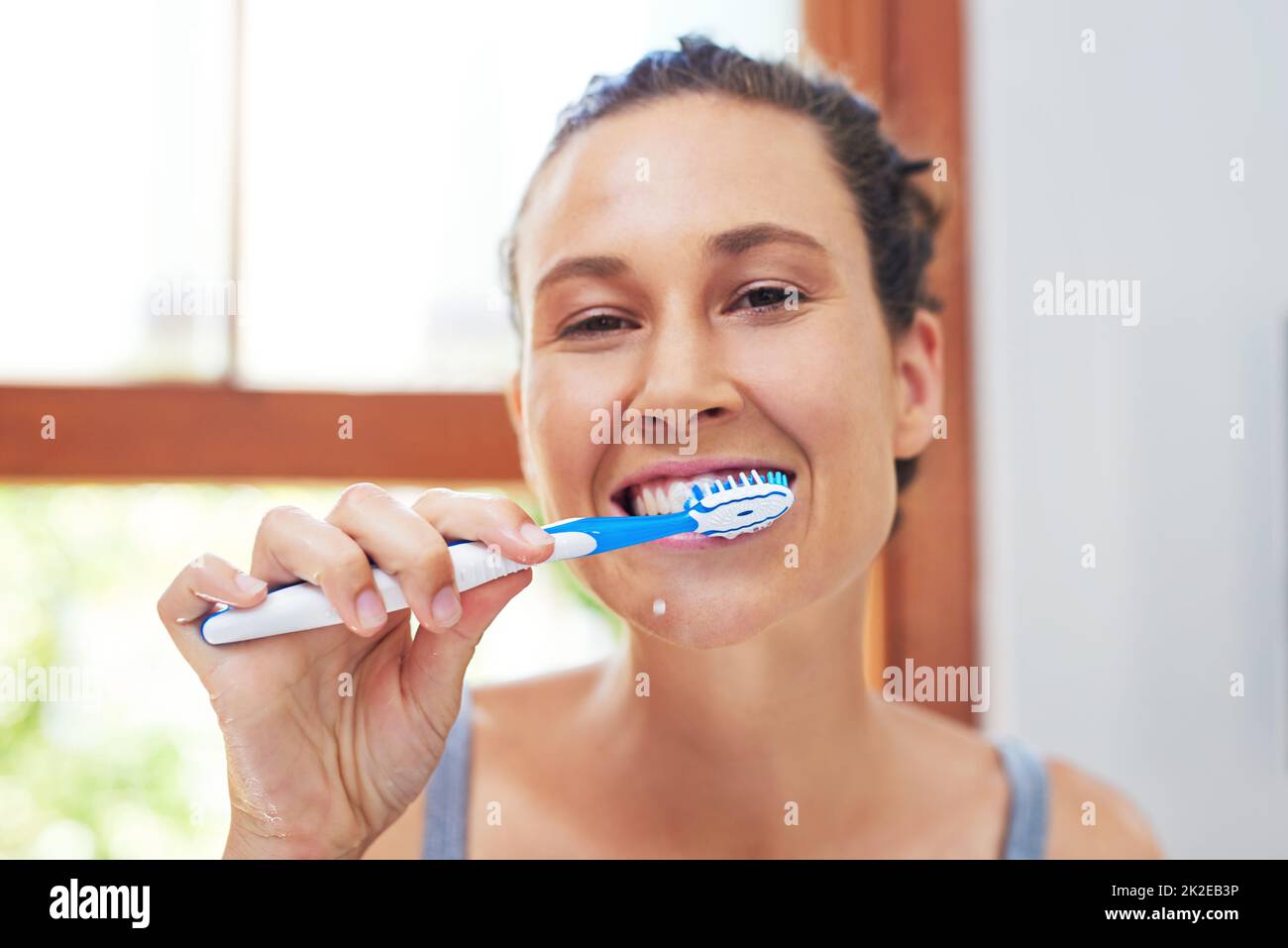 L'hygiène dentaire est extrêmement importante. Portrait d'une jeune femme attirante se brossant les dents à la maison. Banque D'Images
