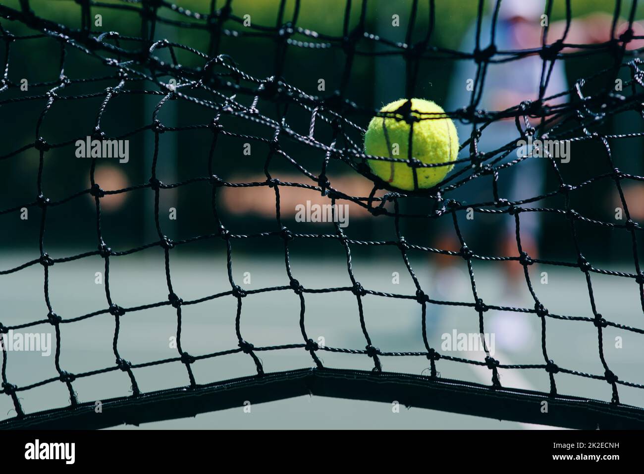 C'est un point perdu. Coupe courte d'une balle de tennis frappant un filet de tennis sur le court pendant la journée. Banque D'Images