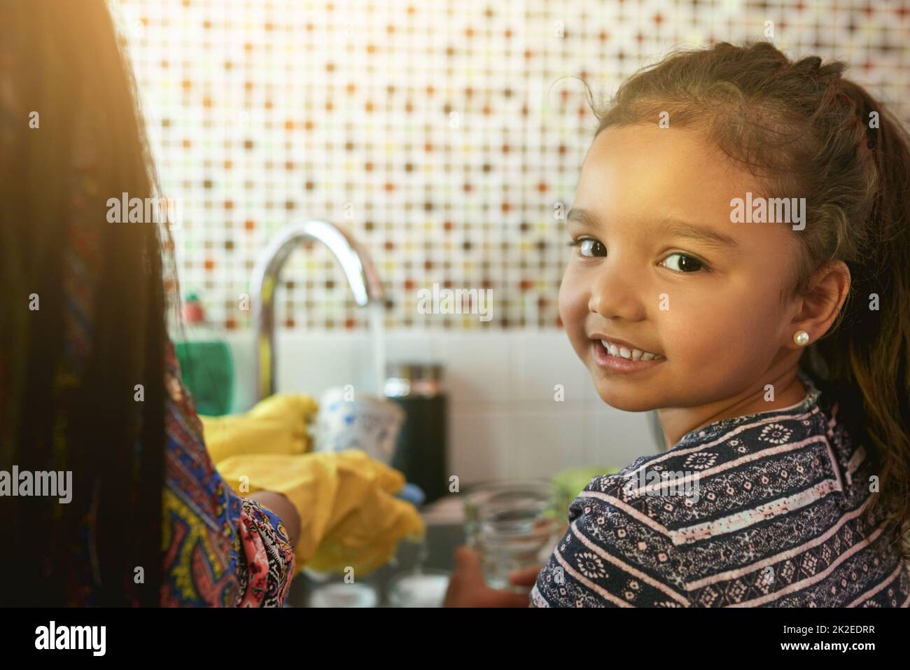 Elle aime aider autour de la maison. Portrait d'une jeune fille lavant des plats dans un kicthen. Banque D'Images
