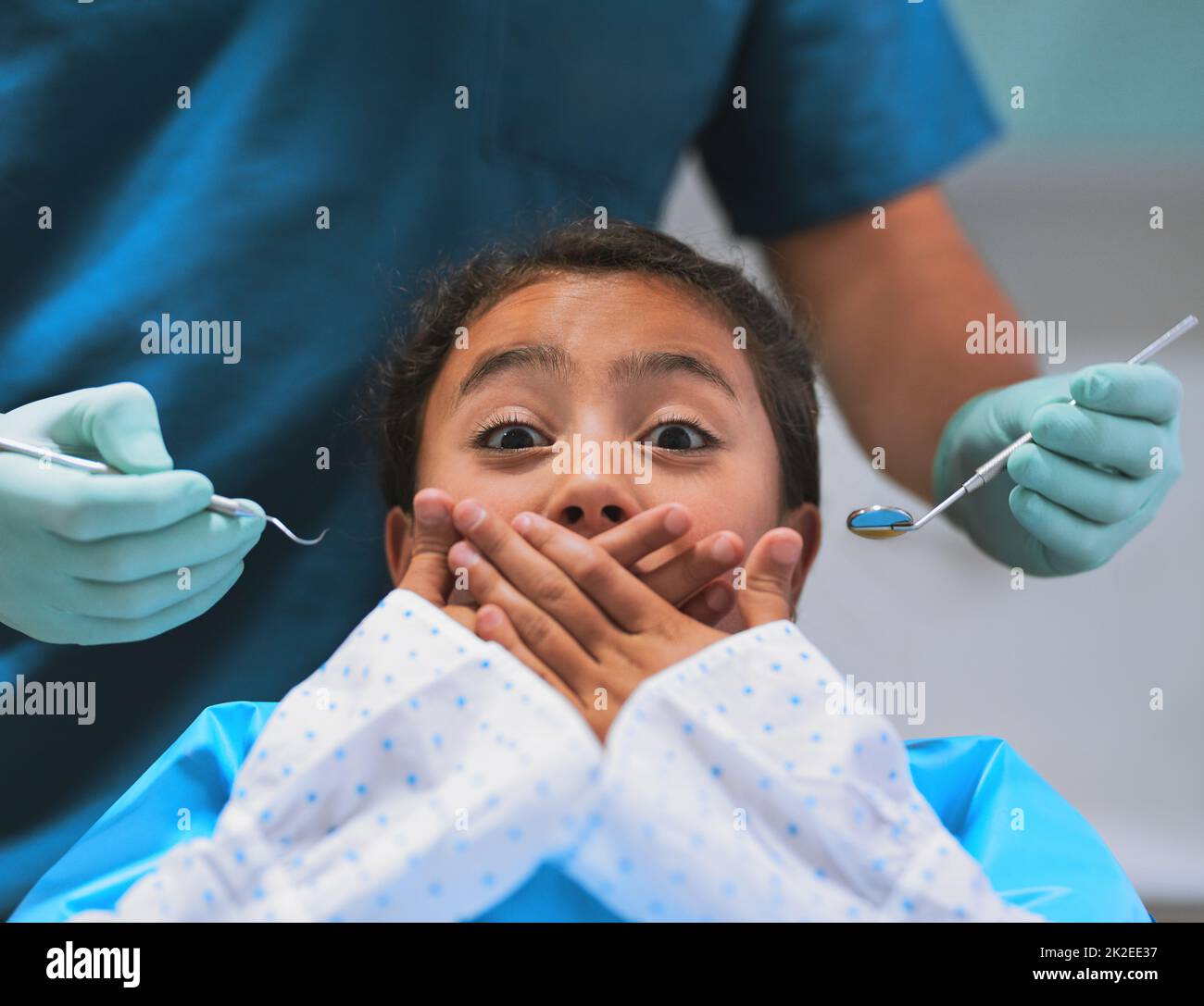 Je ne pense pas que je suis prêt pour cela. Photo d'une petite fille effrayée couchée sur une chaise de dentiste et maintenant sa bouche fermée pour empêcher le dentiste de travailler sur elle. Banque D'Images