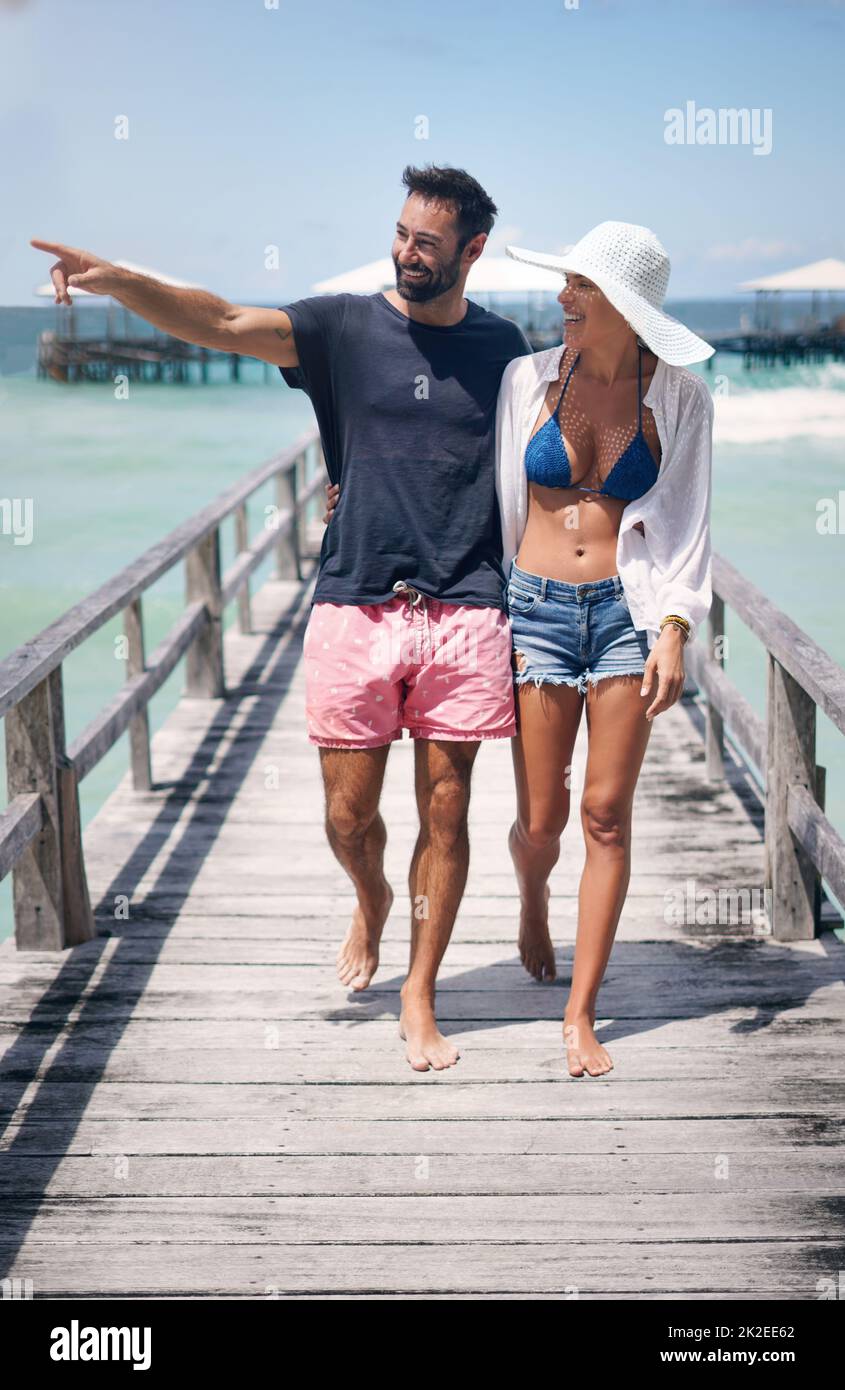 Laisse Va là-bas. Vue en longueur d'un jeune couple heureux marchant bras dans bras sur une promenade pendant une vacances ensemble. Banque D'Images