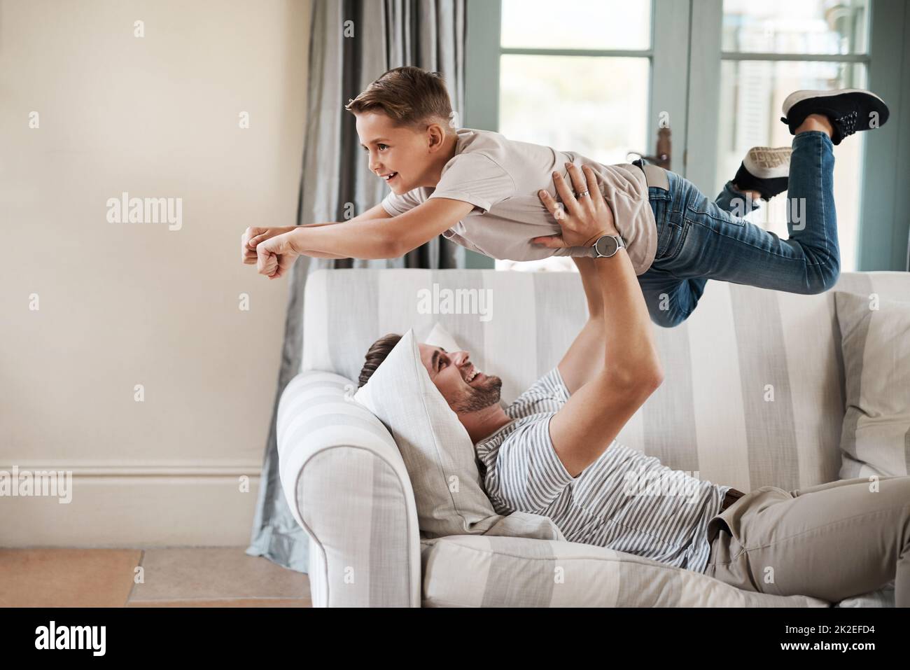 Donnez-leur des ailes pour voler. Photo d'un adorable jeune garçon et de son père jouant ensemble sur le canapé à la maison. Banque D'Images