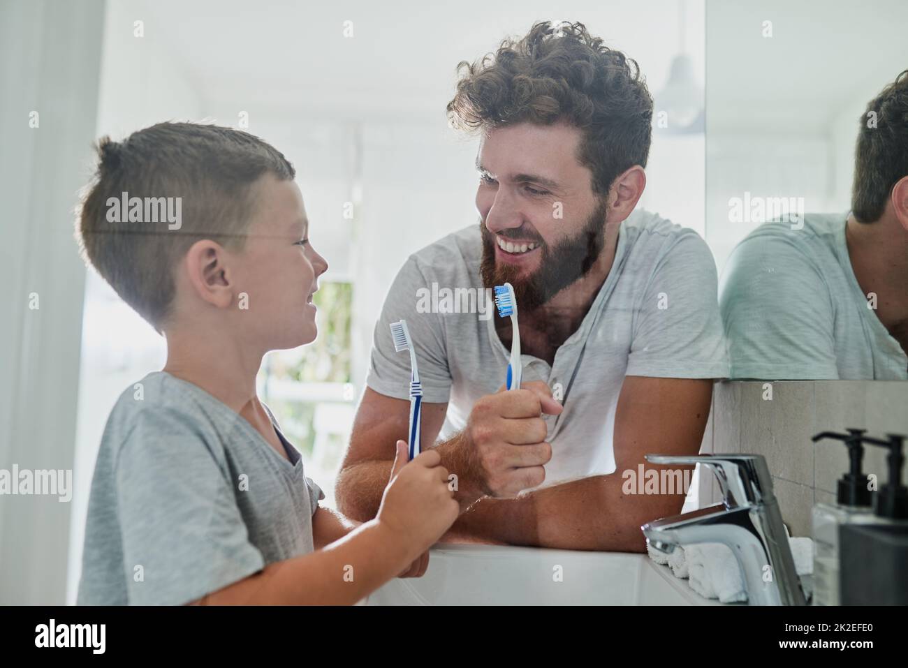 Il faut prendre soin de nos dents. Coup de feu d'un père et de son petit fils se brossant les dents ensemble dans la salle de bains à la maison. Banque D'Images