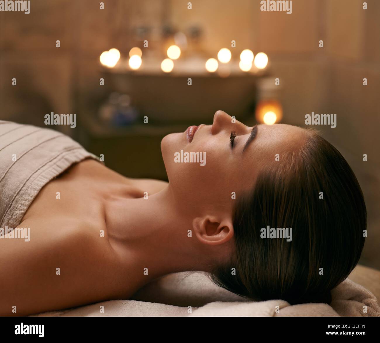 Se faire dorloter de haut en bas. Une jeune femme couché avec les yeux fermés sur un lit de massage. Banque D'Images