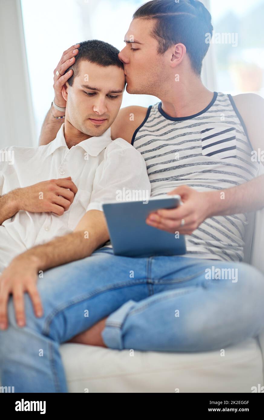 Le temps ensemble est toujours un bon moment. Photo d'un couple gay affectueux à l'aide d'une tablette numérique tout en se relaxant sur le canapé à la maison. Banque D'Images