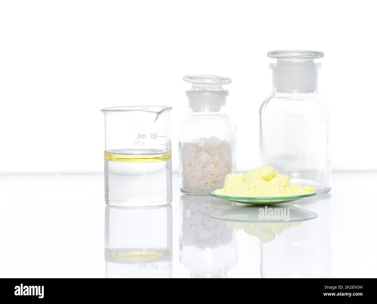 Gros plan sur l'ingrédient chimique sur la table de laboratoire blanche. Poudre de soufre dans le verre de surveillance chimique placer à côté de l'huile dans le bécher et sel de flage dans le verre de bouteille de réactif chimique. Vue latérale Banque D'Images