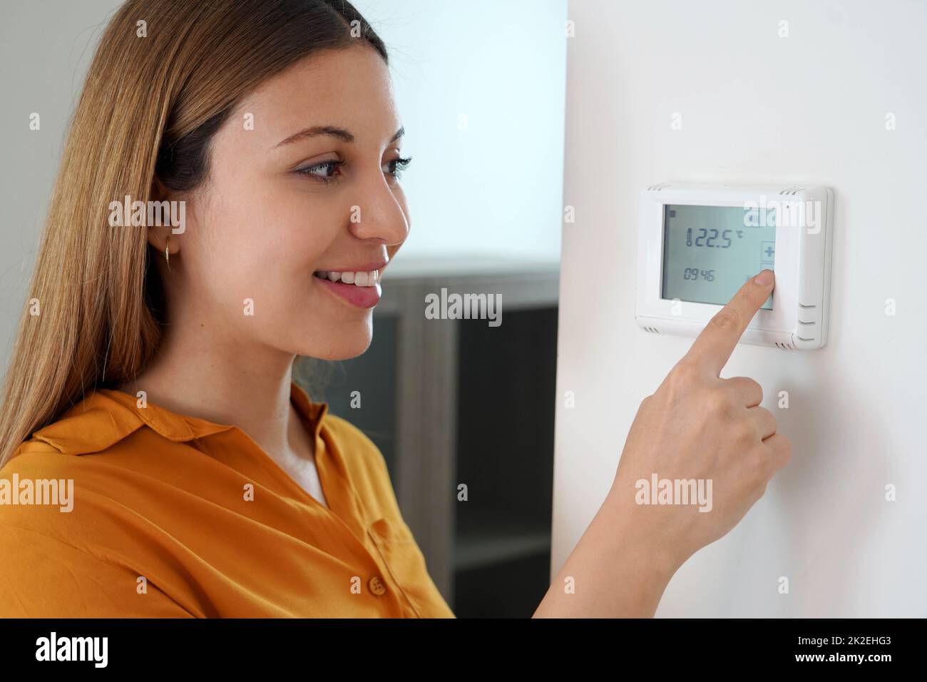 Gros plan de la jeune femme réglant la température du chauffage central à la maison sur le thermostat. Réduire la température pour économiser l'énergie. Banque D'Images
