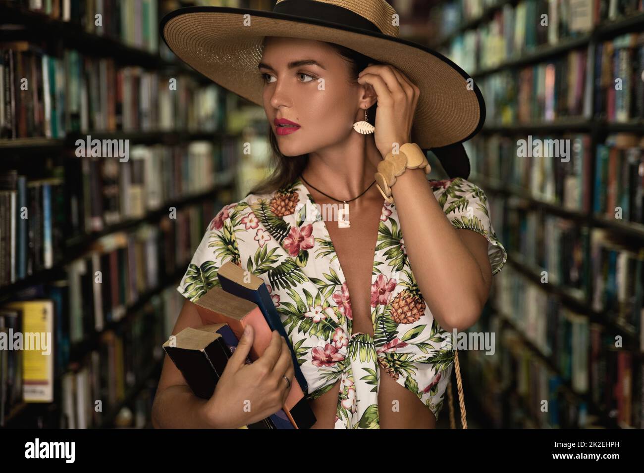 Belle fille portant ensemble élégant à la recherche d'un livre intéressant dans la librairie vintage Banque D'Images