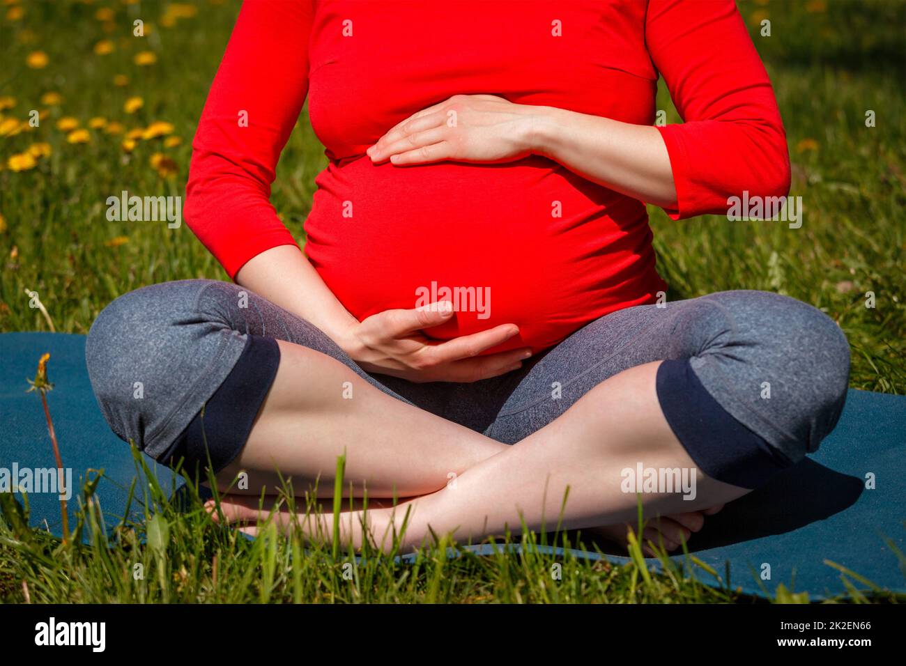 Femme enceinte faisant asana Sukhasana à l'extérieur Banque D'Images