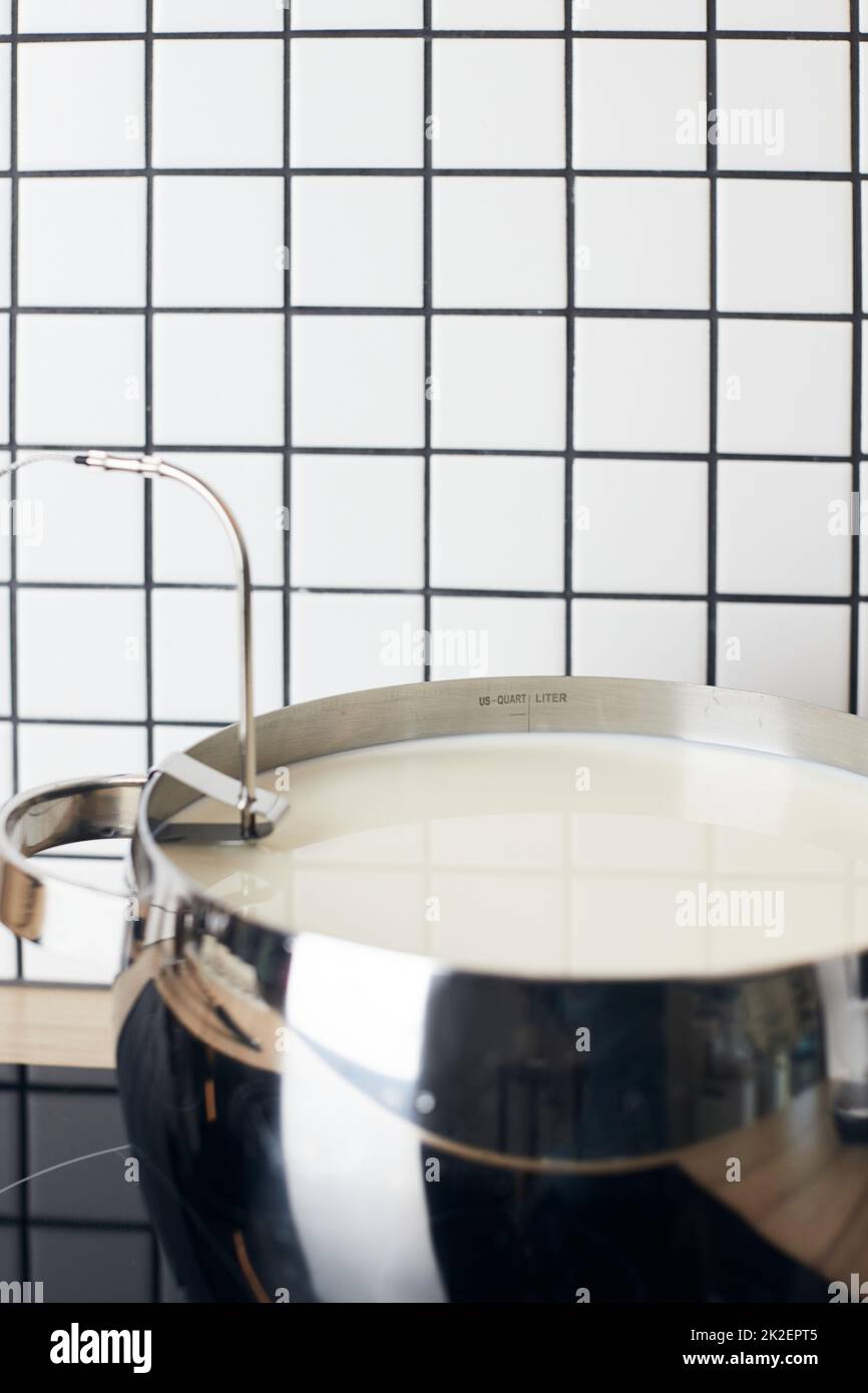 Le processus de fabrication du yaourt. Le lait est chauffé et fermenté par des bactéries. Lait dans une casserole sur la cuisinière. Photo verticale. Banque D'Images