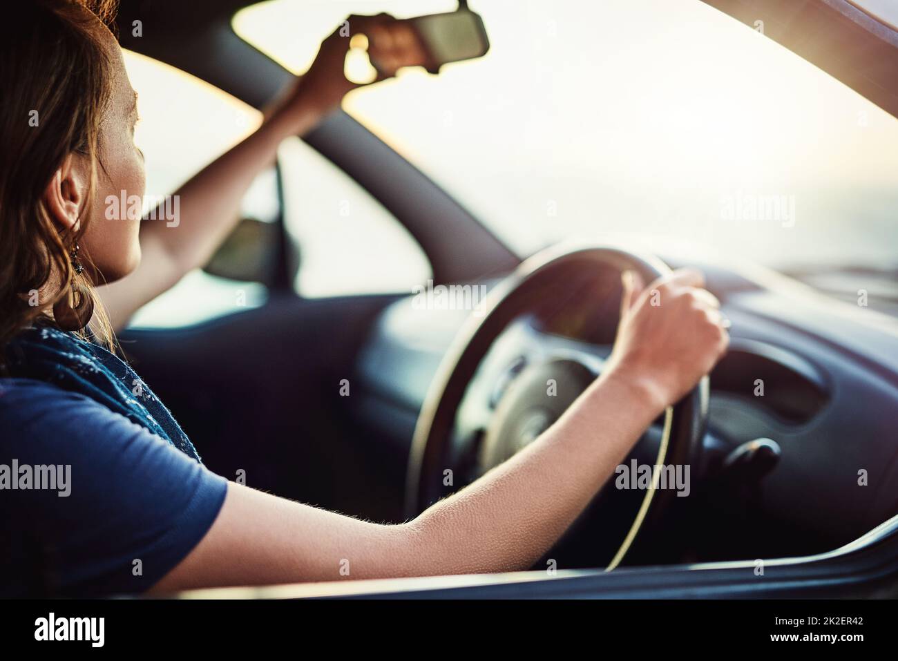 S'assurer qu'elle a une vue claire de son environnement. Photo courte d'une jeune femme qui règle le rétroviseur intérieur de sa voiture. Banque D'Images