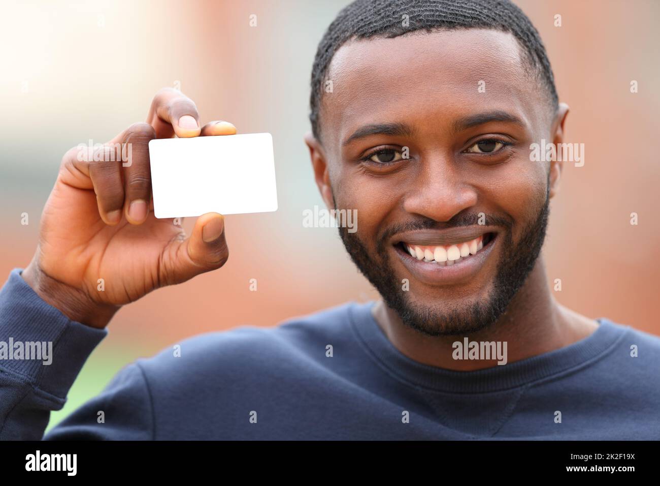 Un homme heureux avec une peau noire montrant une carte de crédit vierge Banque D'Images