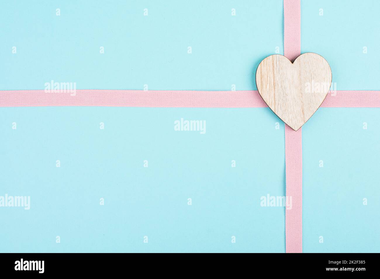 Coeur en bois sur fond rose et bleu clair, fond de vacances, jour de la Saint Valentin, symbole de l'amitié, de l'amour et de la charité Banque D'Images