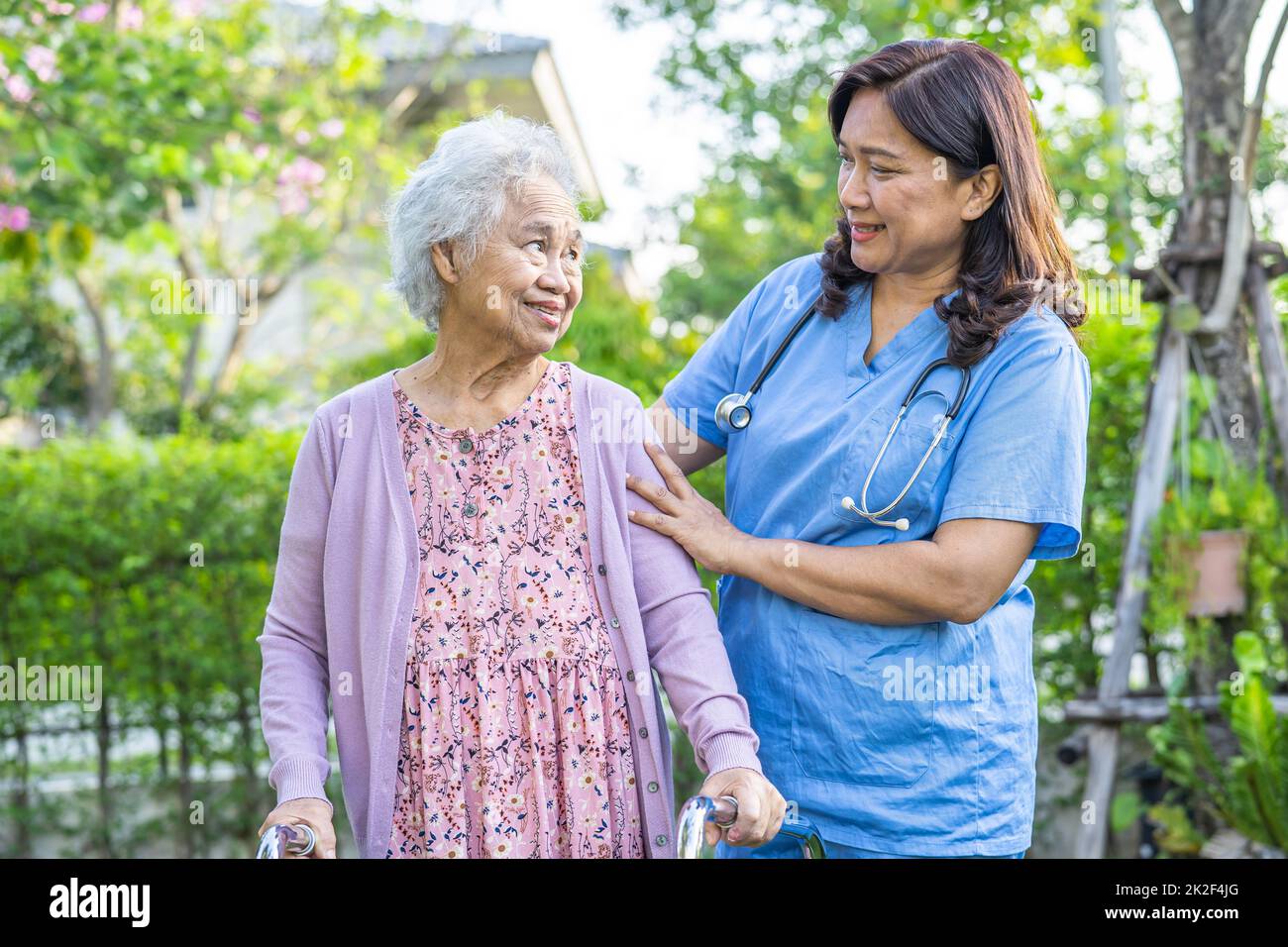 Médecin aide et soins Asian senior ou âgée femme utilisation de marcheur avec une bonne santé tout en marchant au parc dans de bonnes vacances fraîches. Banque D'Images