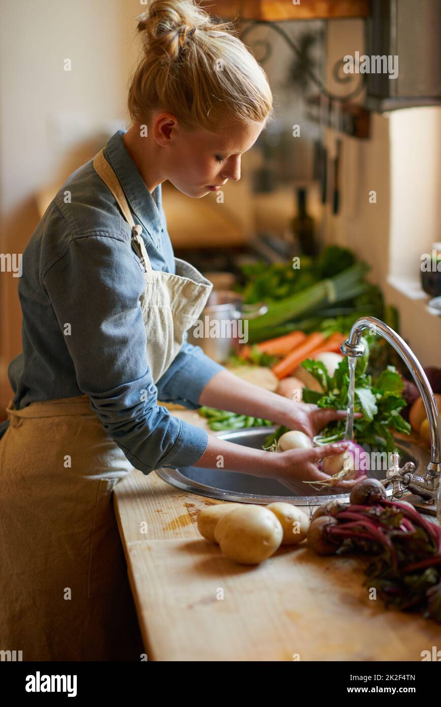 La cuisine est une passion Photo d'une jeune femme lavant des légumes dans un évier. Banque D'Images