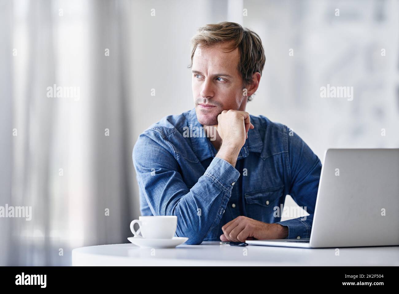 HES un homme d'idée. Photo d'un homme d'affaires mûr et réfléchi utilisant un ordinateur portable tout en étant assis à un bureau. Banque D'Images