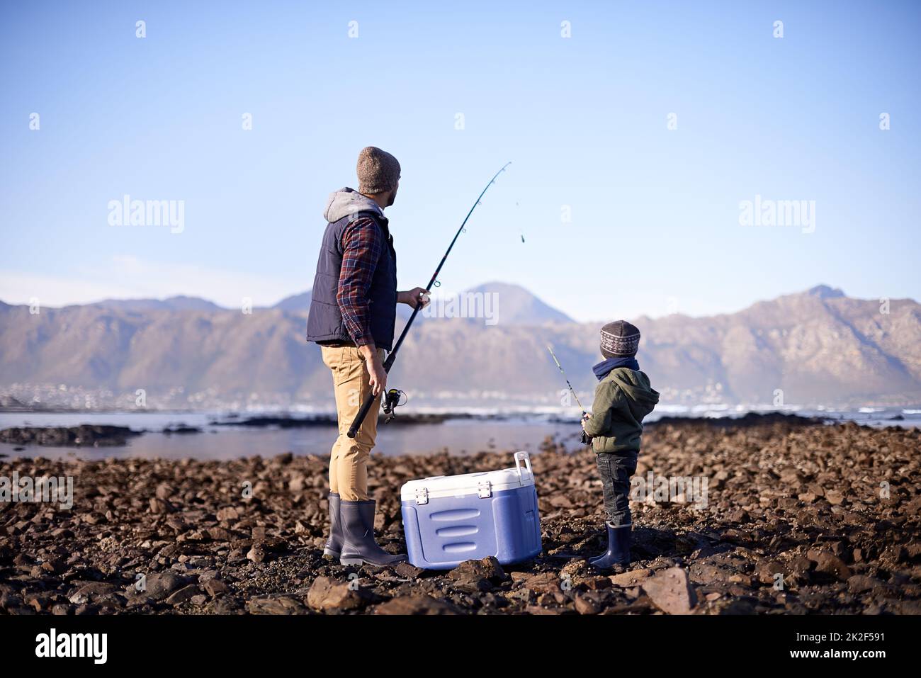 Laisse-le plonger dans la profondeur. Photo d'un père et d'un fils debout avec leur équipement de pêche au bord de la mer. Banque D'Images