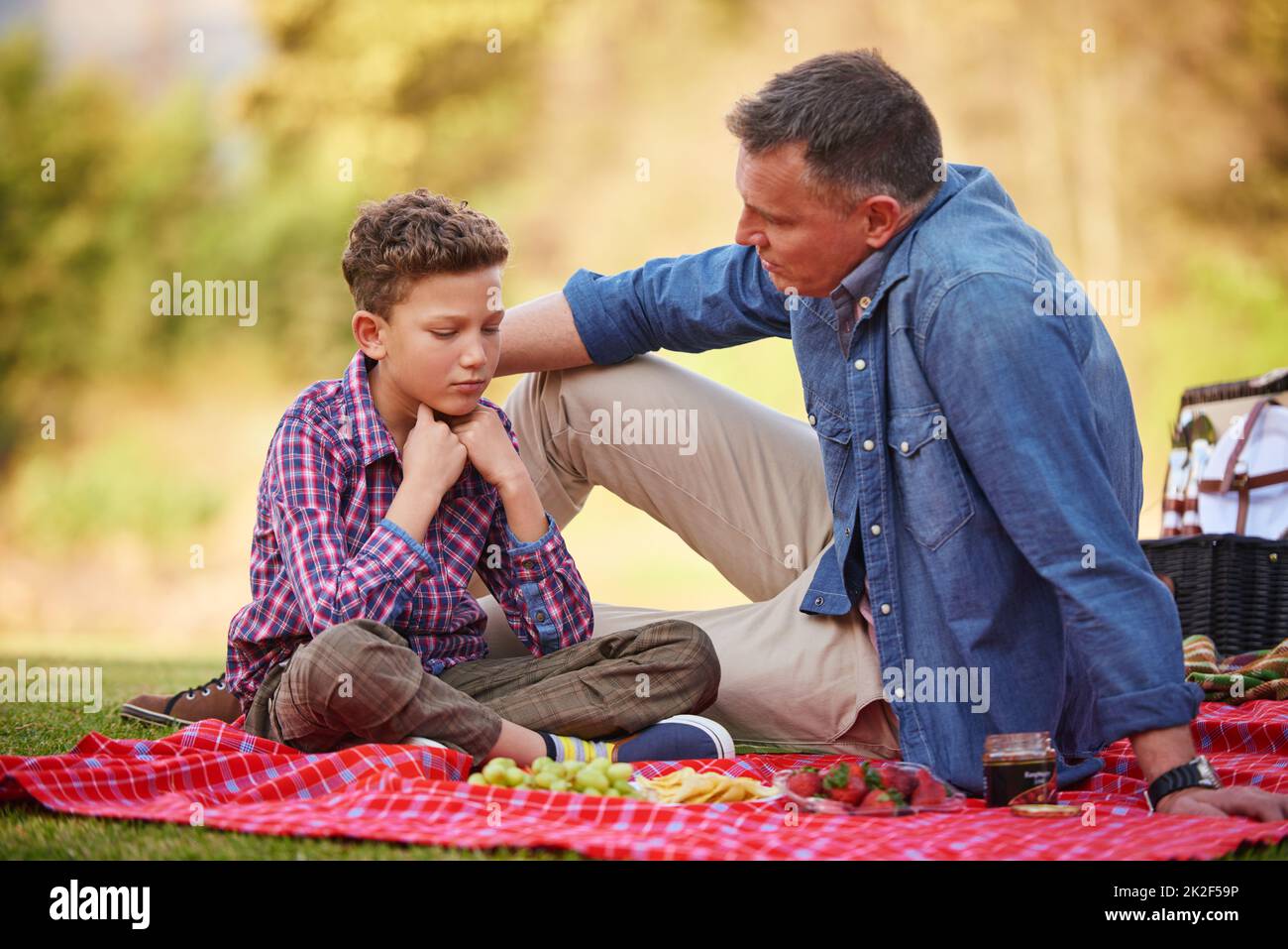 Son père est toujours là pour lui. Photo d'un père réconfortant son jeune fils assis dans un parc. Banque D'Images