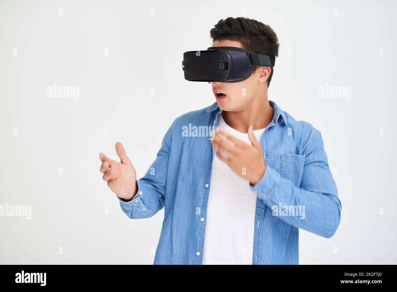 Échappez-vous dans le cyberespace. Prise de vue en studio d'un jeune homme qui a l'air stupéfié tout en portant un casque VR sur fond blanc. Banque D'Images