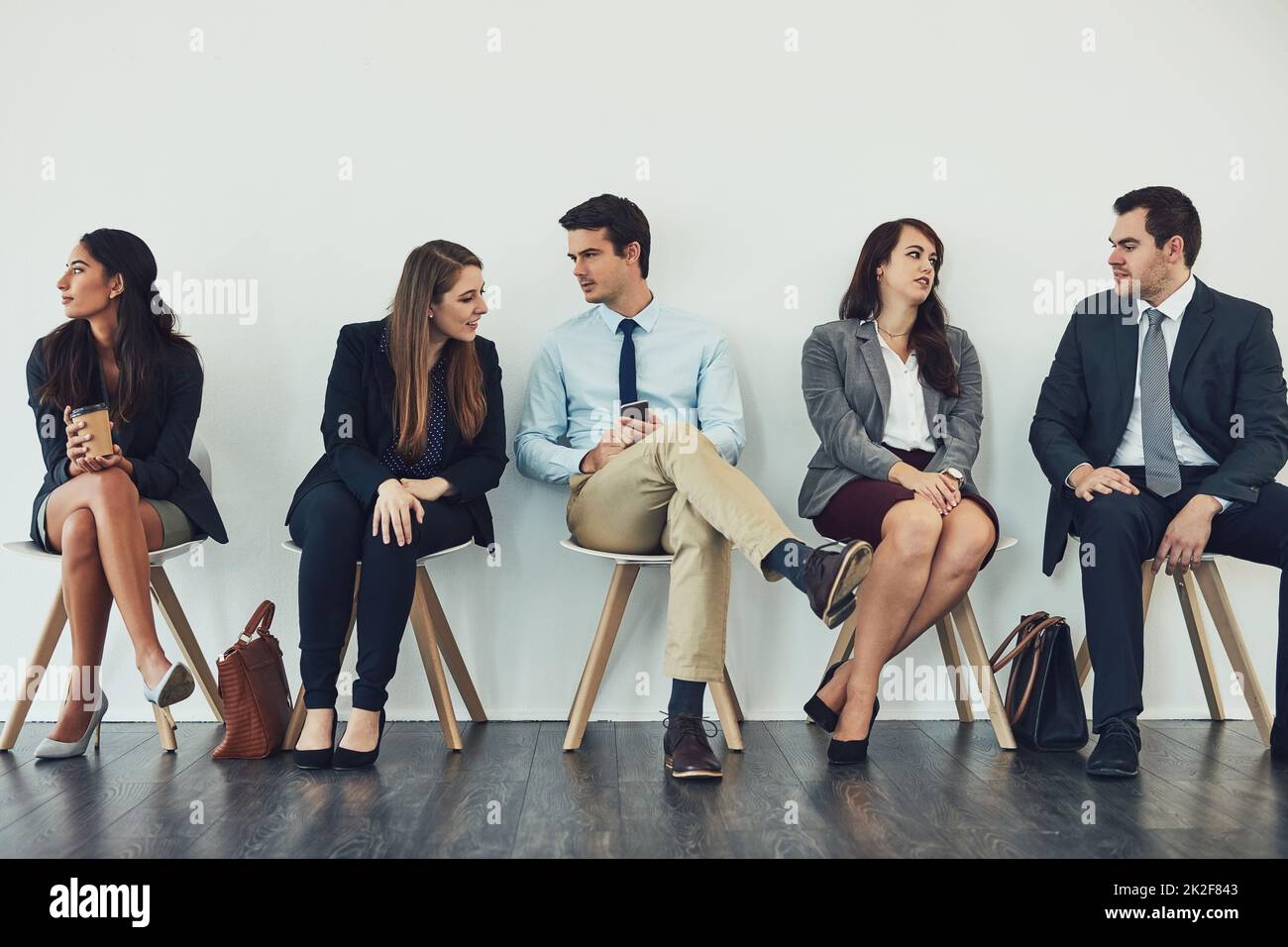 Se connecter à la concurrence. Photo studio d'un groupe de personnes en voyage d'affaires parlant en attendant dans la file d'attente. Banque D'Images