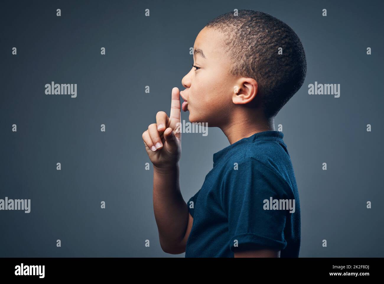 Je peux garder un secret si vous le pouvez. Studio photo d'un petit garçon mignon posant avec son doigt sur ses lèvres sur un fond gris. Banque D'Images