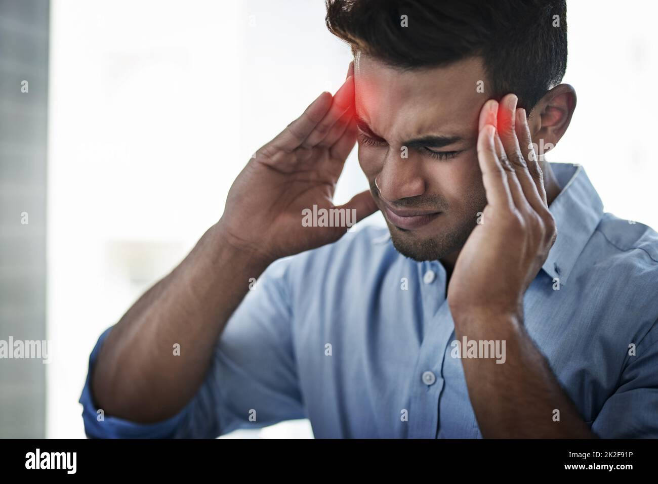 Cette douleur est si intense. Photo d'un jeune homme d'affaires souffrant d'un mal de tête au travail. Banque D'Images