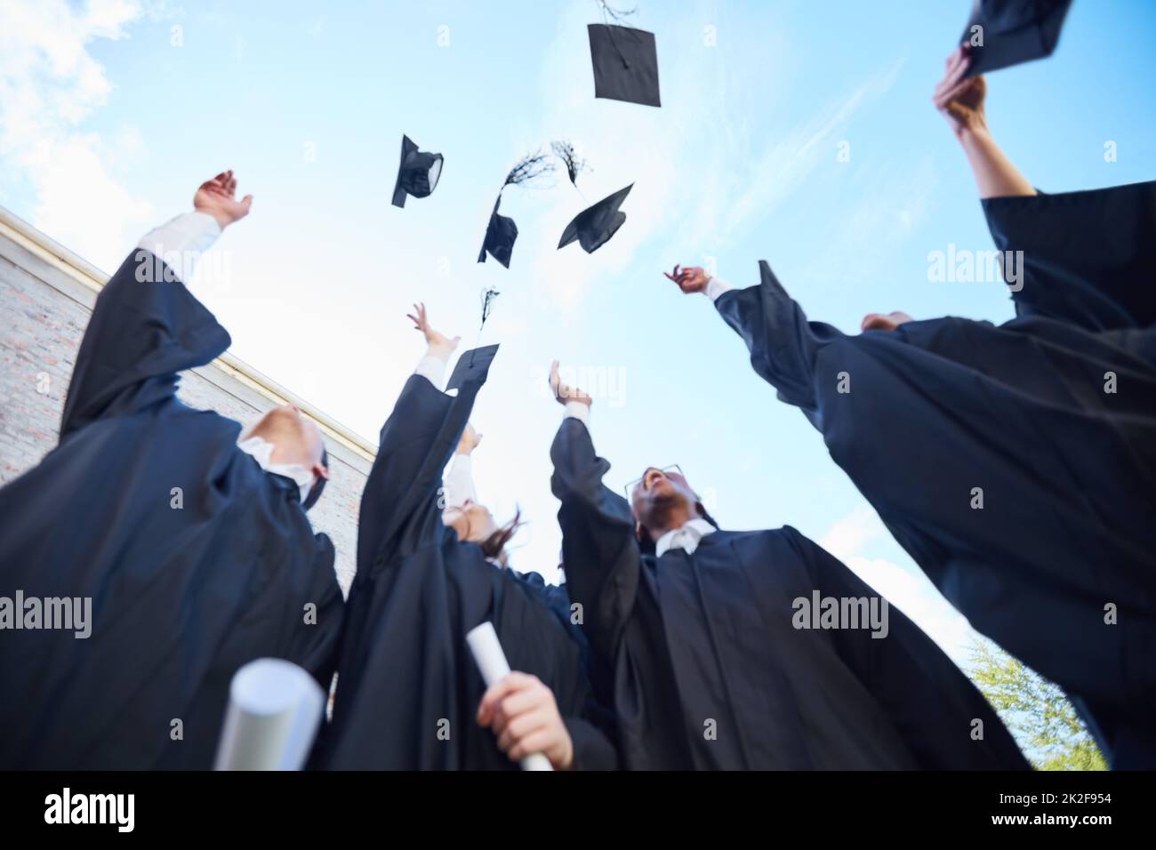 Au prochain chapitre de nos vies. Photo à angle bas d'un groupe d'élèves qui jettent leurs casquettes dans les airs le jour de la remise des diplômes. Banque D'Images