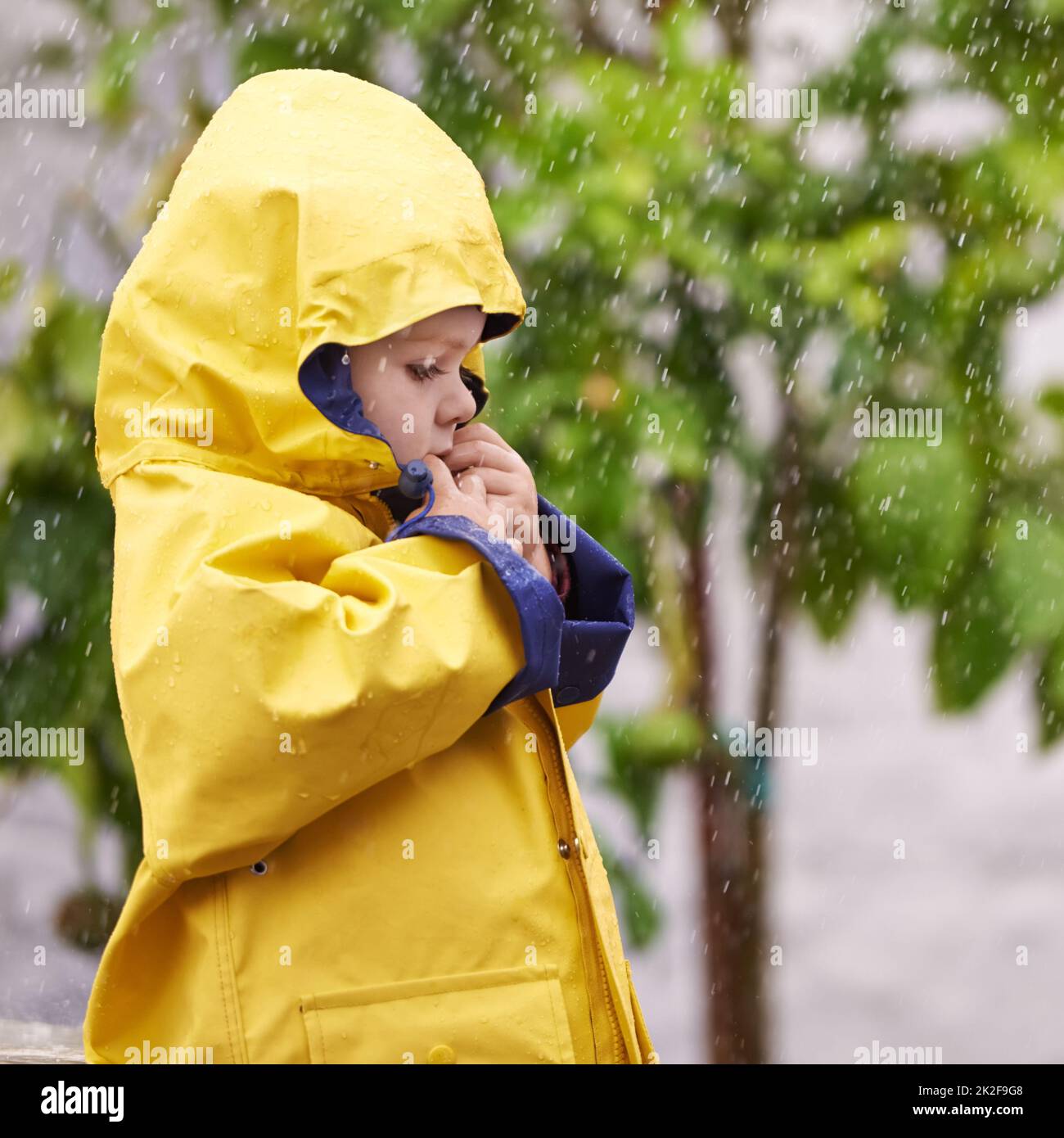 Cet hiver, il est imperméable. Un adorable petit garçon jouant dehors sous la pluie. Banque D'Images