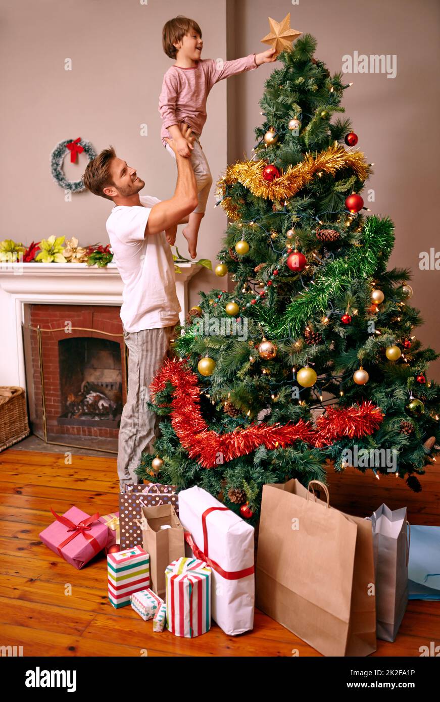 C'est une tradition familiale Un père levant son fils pour mettre l'étoile sur l'arbre de Noël. Banque D'Images