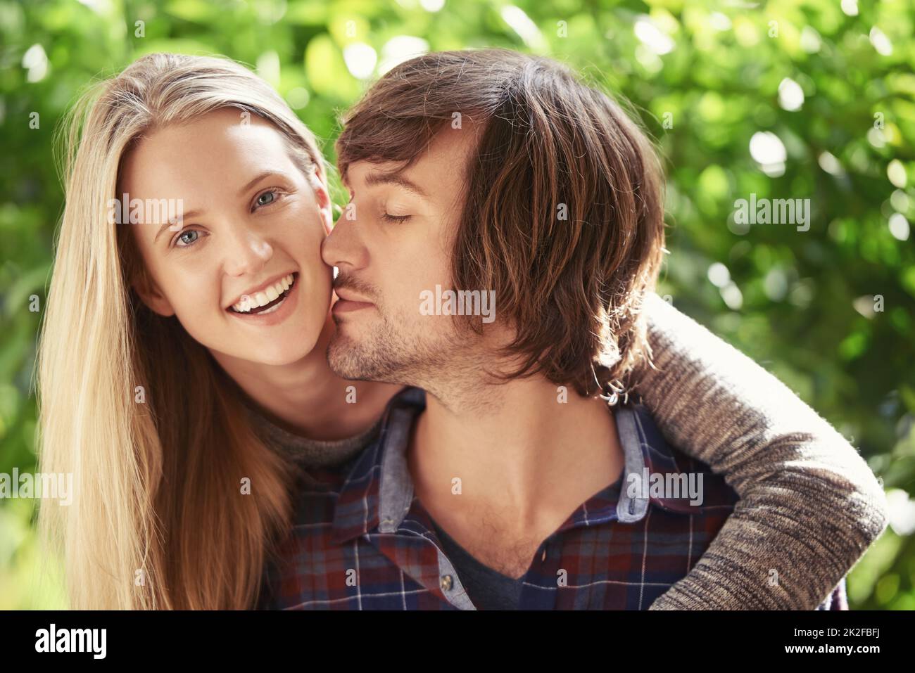 Jeune et plein de passion. Portrait d'un jeune couple souriant qui s'embrasse dans le parc. Banque D'Images