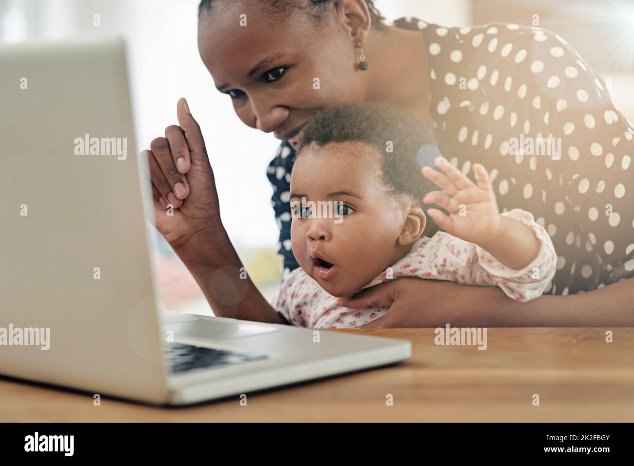 Curieux jeune esprit. Photo d'une mère et de sa petite fille assise devant un ordinateur portable. Banque D'Images