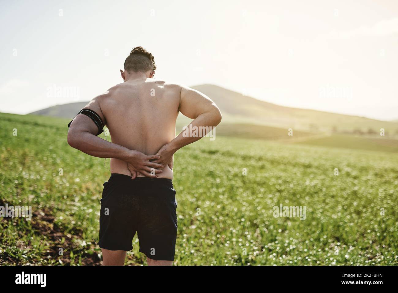 HES lui a blessé le dos. Vue arrière d'un jeune homme tenant son dos dans la douleur pendant une course. Banque D'Images