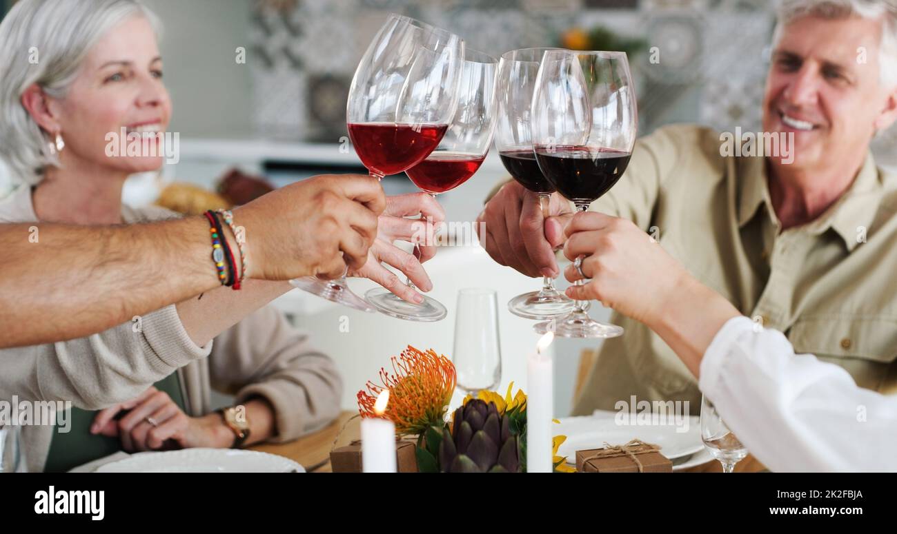 Heres à des amis qui se sentent comme la famille. Photo de deux couples heureux assis pour le déjeuner et toaster avec des verres à vin à la maison. Banque D'Images