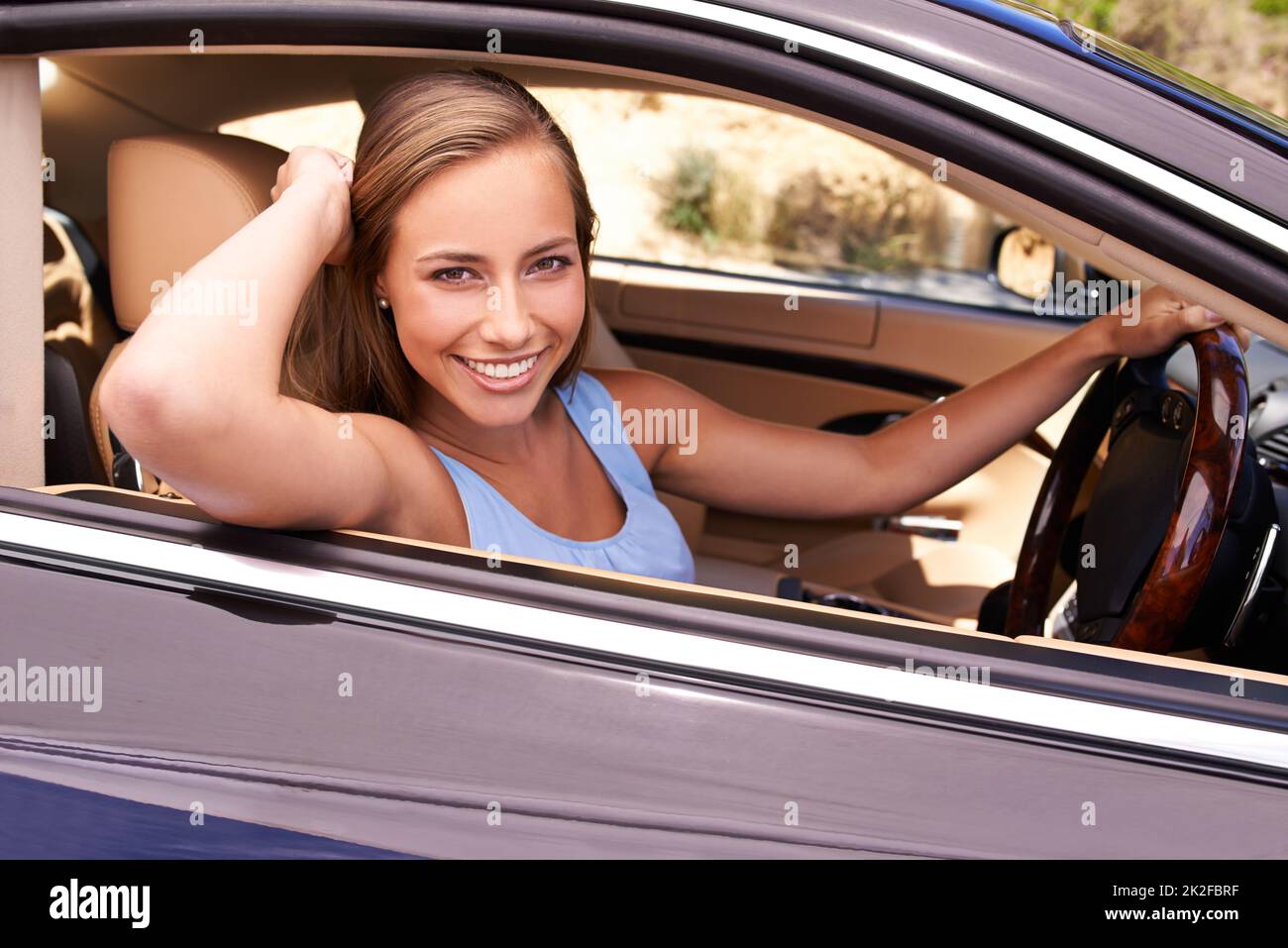 Je suis à la maison derrière le volant. Une femme assise dans une voiture de luxe. Banque D'Images