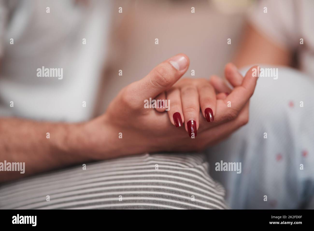 Main dans la main. Photo courte d'un couple méconnaissable tenant les mains affectueusement à la maison. Banque D'Images