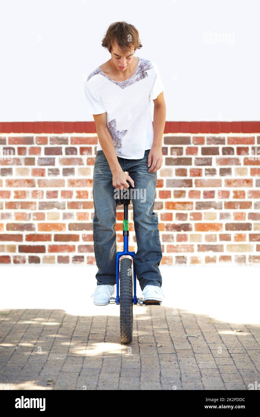 HES a des compétences. Photo en pleine longueur d'un jeune homme qui se balance sur un monocycle. Banque D'Images