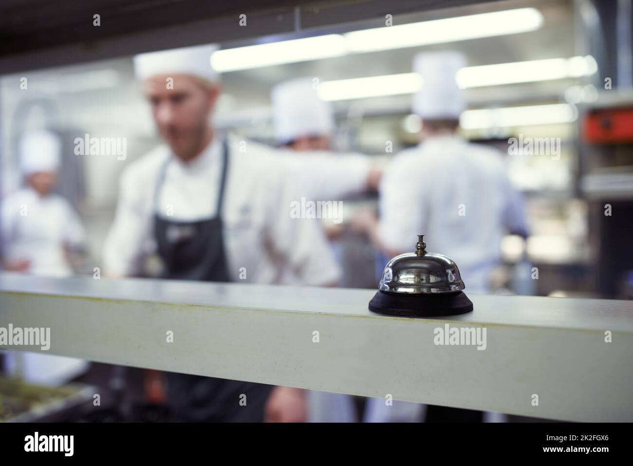 Service. Prise de vue de chefs préparant un service de repas dans une cuisine professionnelle. Banque D'Images