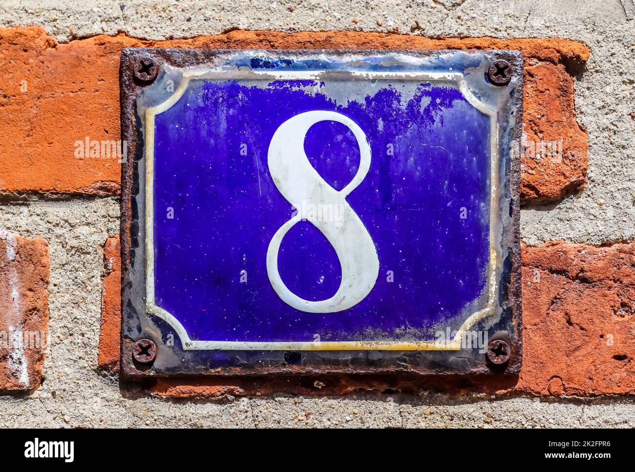 Vieux mur de briques. Texture d'un vieux mur de briques avec un numéro 8 sur un signe bleu. Banque D'Images