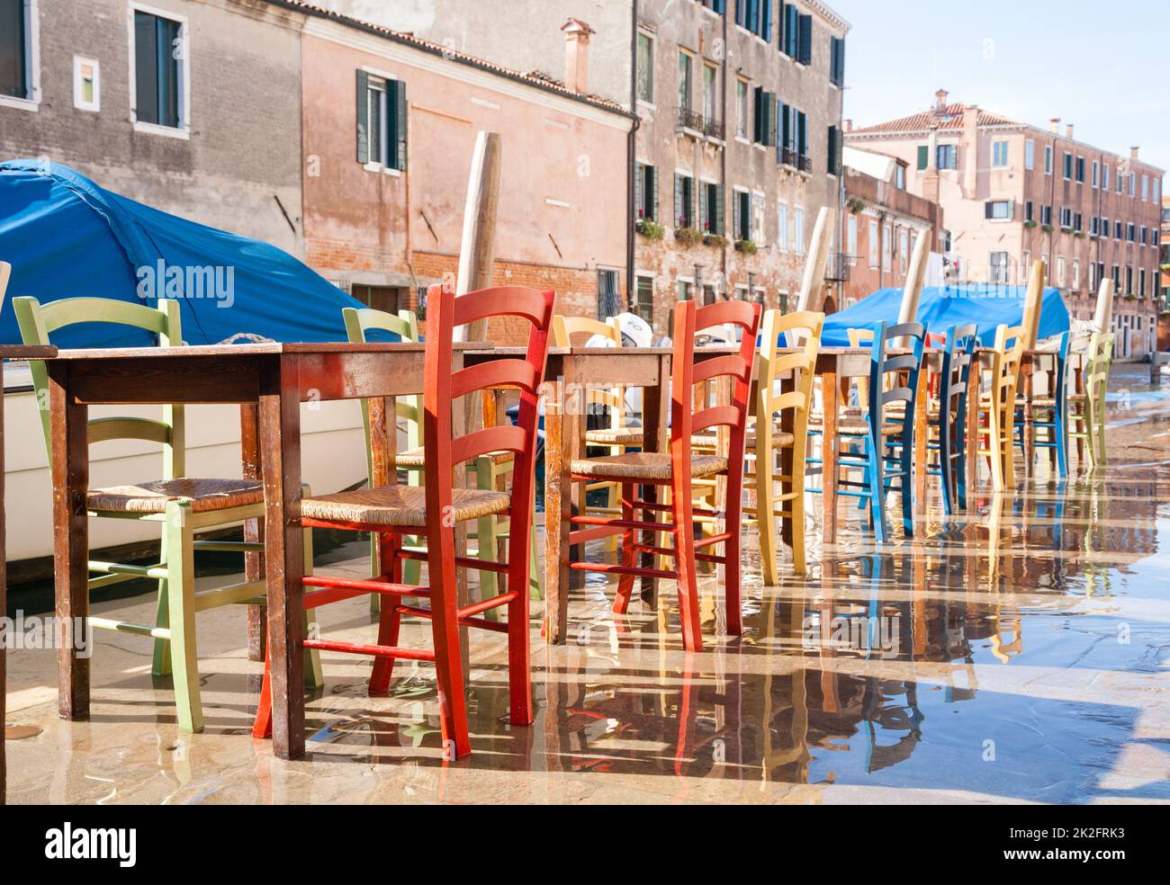 Chaises colorées dans une rangée le long du canal vénitien Banque D'Images