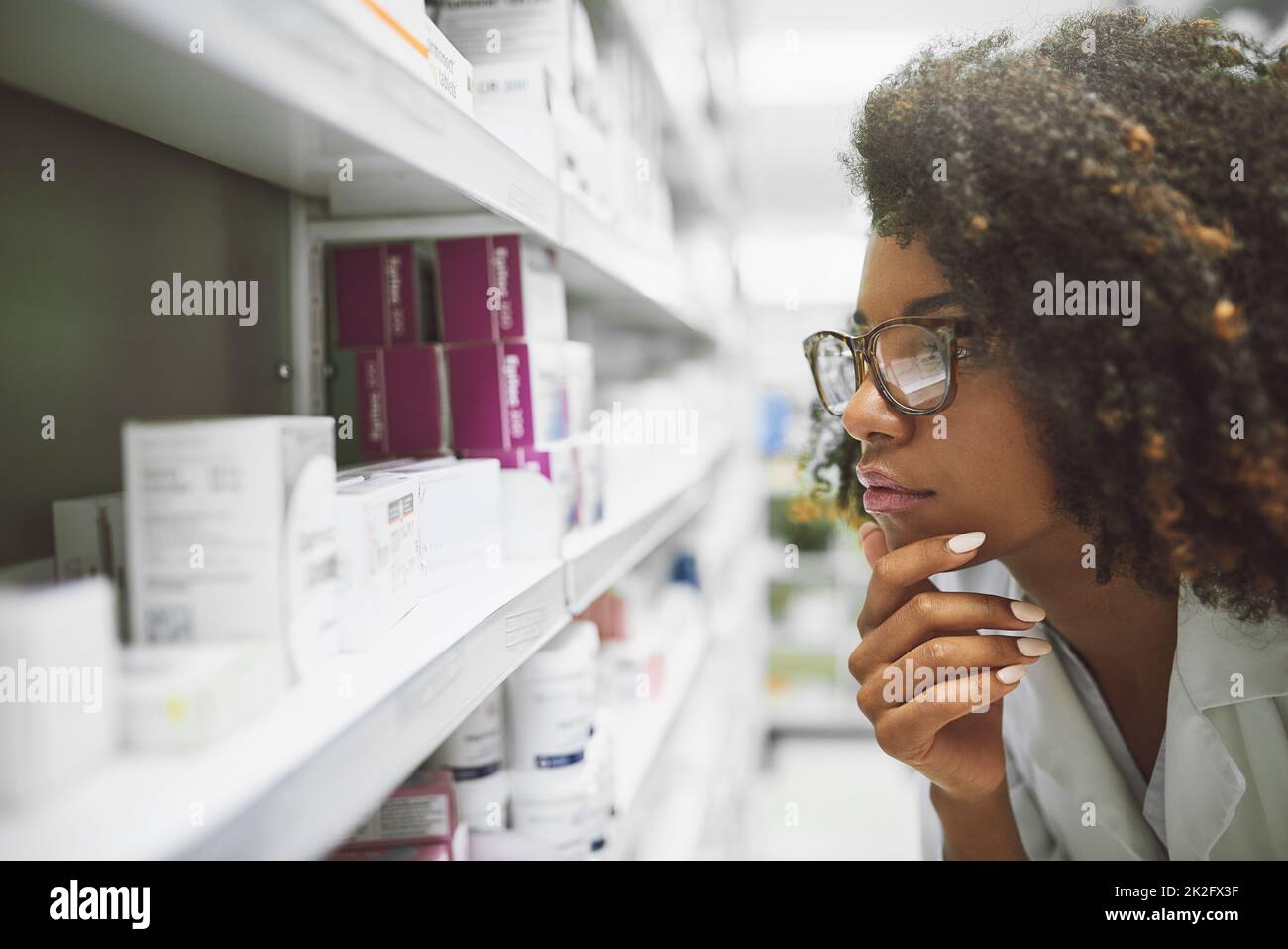 Ce petit gars semble être perdu. Prise de vue d'une jeune pharmacienne ciblée regardant de près les médicaments sur une étagère à l'intérieur d'une pharmacie. Banque D'Images